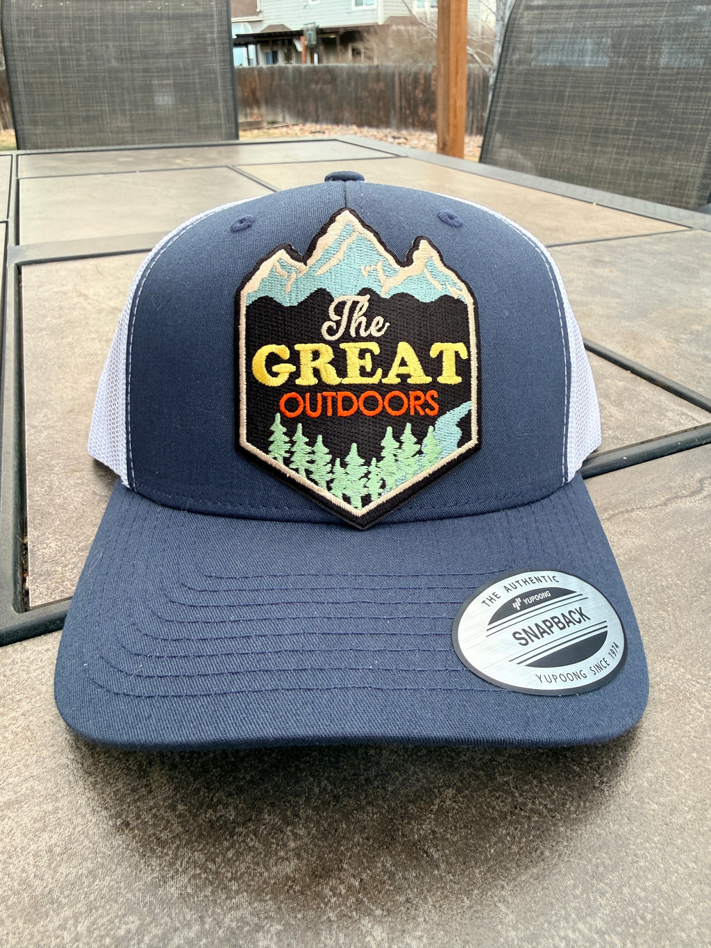 Navy and white trucker hat with The Great Outdoors mountain patch flat lay – personalized hat – Hedrick Hat Co